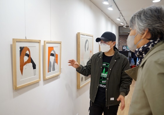 김영화 작가(왼쪽)이 유디갤러리를 방문한 관객에게 작품을 설명하는 모습 (사진 = 유디치과)