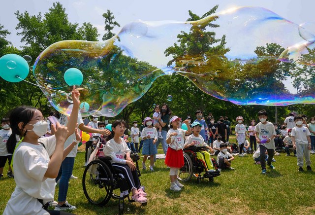5월 21일 서울올림픽공원에서 열린 2022 상상인 피크닉데이에서 휠체어 사용 아동 이동성 향상 프로젝트 참여 아동과 가족들이 버블쇼를 즐기고 있다. (사진 = 상상인)