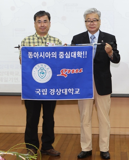 NSP통신-하우송 경상대학교 총장이 정헌수 단장에게 경상대학교 깃발을 전달하며 격려하고 있다. <사진제공=경상대학교>