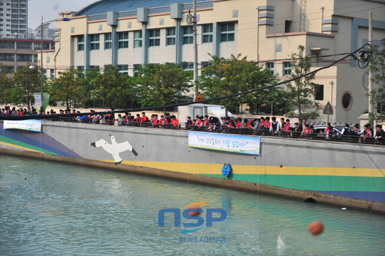 NSP통신-성동중학교 앞 동천변에 길게 줄지어 선 학생들이 흙공을 동천에 던지고 있다. (임은희 기자)