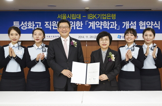 NSP통신-권선주 은행장(오른쪽 세 번째)과 이건 서울시립대 총장이 지난달 28일 오후 서울 중구 을지로 본점에서 특성화고 직원의 후진학을 위한 정규학과 개설 협약식을 마치고 특성화고 직원들과 기념촬영을 하고 있다.