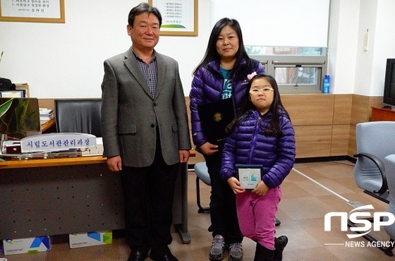 NSP통신-29일 김홍식 군산시립도서관장(왼쪽)이 책 읽는 가족에 선정된 송한진씨 가족에게 인증서 및 현판을 전달하고 있다.