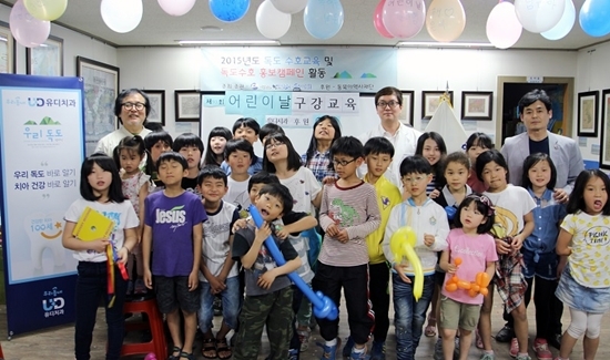NSP통신-길종성 독도사랑회 이사장(뒤 오른쪽)과 노래 독도는 우리 땅의 가수 정광태 교수(뒤 왼쪽)가 유디치과 고광욱 대표원장뒤 가운데)의 다문화 가정 아이들을 위한 치아건강 교실을 개최 후 기념사진을 찍고 있다.