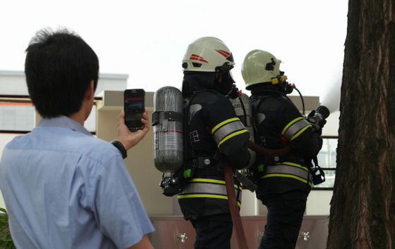NSP통신-삼성전자 응급 구조대원이 화재가 난 건물을 진화하는 장면을 재난망용 스마트폰으로 중앙관제소에 실시간으로 전송하고 있다.