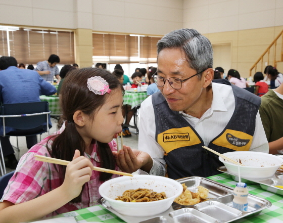 NSP통신-국민은행 윤종규 은행장이 초청 아동에게 탕수육을 먹여주는 모습