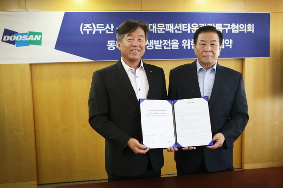 NSP통신-㈜두산 사업부문 동현수 사장 (왼쪽)과 홍석기 (사)동대문패션타운 관광특구협의회 회장이 업무협약을 체결하고 기념사진을 찍고 있다.