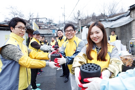 NSP통신-OCI 신입사원과 임원들이 멘토링의 일환으로 서울 중계동 백사마을에서 연탄을 나르고 있다.