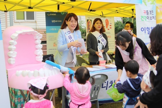 NSP통신-유디치과 충주점 치위생사가 아이들에게 구강건강용품을 나눠 주고 있다. (유디치과)