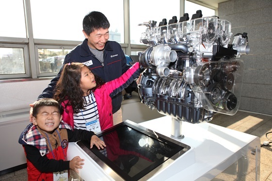 NSP통신-쌍용차 직원이 공장을 방문한 자녀들과 전시된 엔진을 보며 즐거운 시간을 보내고 있다.