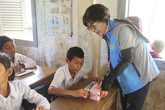 NSP통신-충청남도자원봉사센터의 자원봉사자가 유디치과에서 후원한 구강모형으로 캄보디아 어린이에게 올바른 칫솔질 교육을 하고 있다 (유디치과)