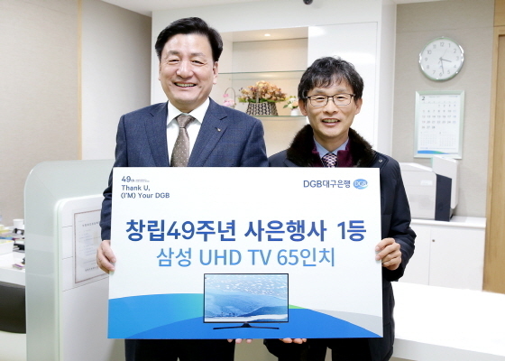 NSP통신-DGB대구은행 성무용 부행장(왼쪽)이 1등 당첨고객 김희철 씨에게 상품을 전달하고 있다. (DGB대구은행)