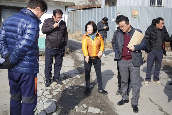 NSP통신-▲이상숙 안산시의회 도시환경위원회 간사(사진 가운데 노란옷)가 장하동 벌말마을 안길 개선과 관련해 시 관계자 및 주민들과 현장을 확인하고 있다 (안산시의회 제공)