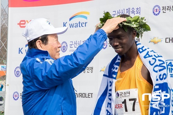 NSP통신-문동신 군산시장(사진 왼쪽)이 2017 군산새만금국제마라톤대회에서 우승을 차지한 엘리샤 킵쳐쳐 로티치(케냐) 선수에게 월계관을 씌워주고 있다.