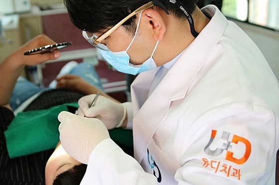 NSP통신-진세식 유디치과협회장이 학생의 치아를 검진 한 후 치료를 하고 있는 모습 (유디치과)