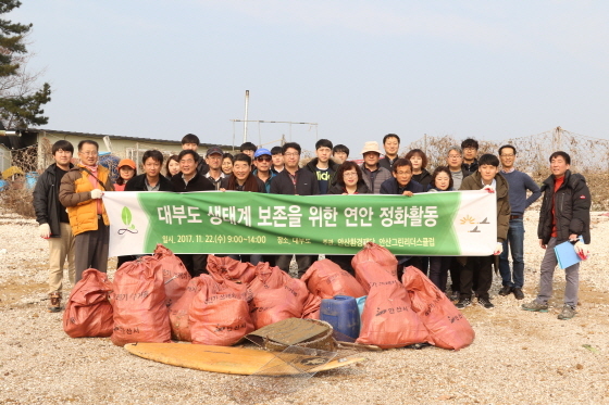 NSP통신-22일 대부도 시화호 연안에서 안산환경재단 임직원을 비롯한 관계자들이 환경정화활동 후 기념촬영을 하고 있다. (안산환경재단)