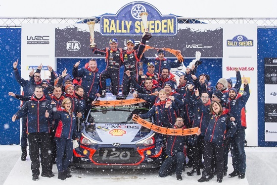 NSP통신-2018 WRC 스웨덴 랠리에서 시상대에서 현대 월드랠리팀 선수 및 관계자들의 기념사진. 신형 i20 랠리카 위에서 니콜라스 질술(Nicolas Gilsoul, 왼쪽)과 티에리 누빌(Thierry Neuville)이 우승컵을 들고 환호하는 모습. (현대차)