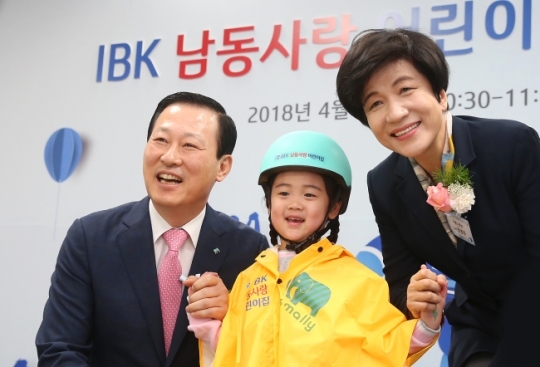 NSP통신-김도진 은행장(왼쪽)과 김영주 고용노동부장관(오른쪽)이 4일 IBK 남동사랑 어린이집 개원식에서 원아에게 선물을 전달하고 기념촬영을 하고 있다. (IBK기업은행)