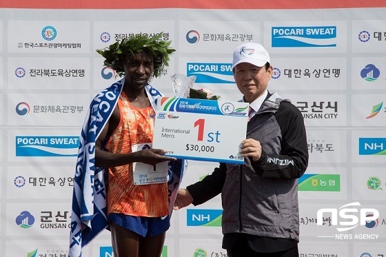 NSP통신-문동신 군산시장(오른쪽)이 2018 군산새만금국제마라톤대회에서 우승을 차지한 케냐 로버트 괌바이 선수에게 우승상금을 전달하고 있다.