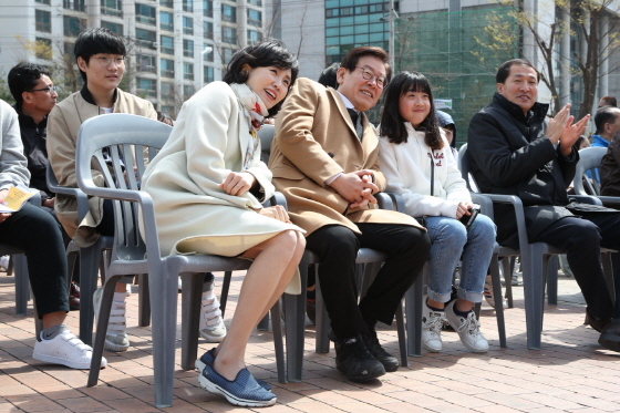 NSP통신-슬립온 신발을 신은 김혜경 여사가 어느 행사장에서 남편인 이재명 예비후보와 함께 의자에 앉아있다. (명캠프)