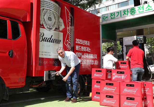 NSP통신-오비맥주 고동우 대표(왼쪽)가 전기차충전소에서 버드와이저 맥주를 운반하는 친환경 전기트럭을 충전하고 있다