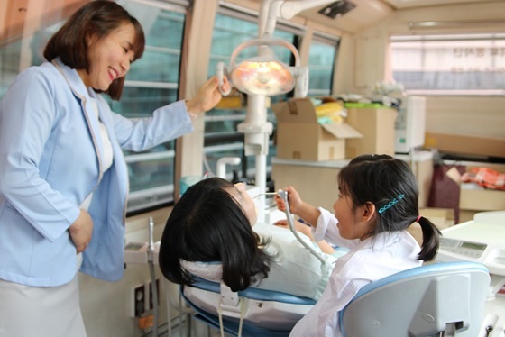 NSP통신-김천희 수원인계 유디치과의원 치위생사가 아이들에게 치과의사 직업체험을 진행하고 있는 모습 (유디치과)