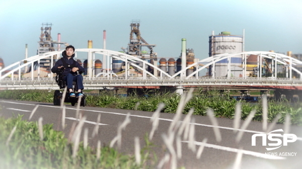 NSP통신-김동현 씨가 포스코 1%나눔재단에서 지원받은 휠체어를 타고 포항제철소를 전경으로 달리고 있다. (포항제철소)
