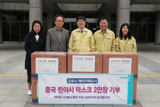 NSP통신-한대희 군포시장(가운데)을 비롯한 시 관계자들이 중국 산동성 린이시에 전달할 마스크와 함께 기념촬영을 하고 있다. (군포시)