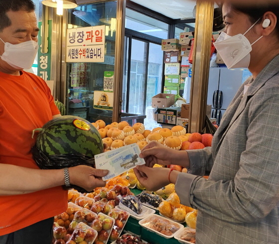 NSP통신-성남 중앙시장에서 캄보디아 출신 결혼이민자가 성남사랑상품권으로 수박을 사고 있다. (성남시)