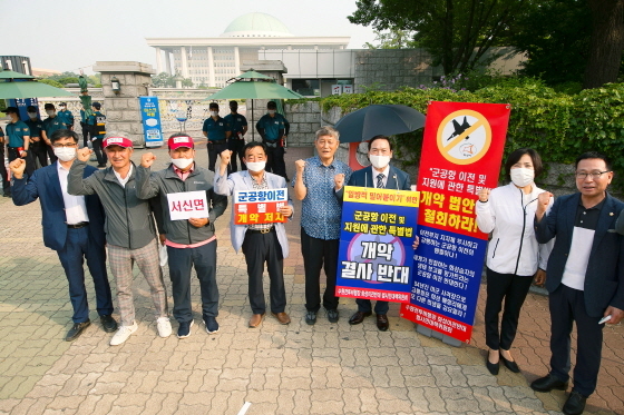 NSP통신-9일 정흥범 화성시의원(오른쪽부터), 박연숙 수원군공항이전반대특별위원회 위원장, 원유민 화성시의회 의장 및 관계자들이 국회 정문 앞에서 시위를 하고 있다. (화성시의회)