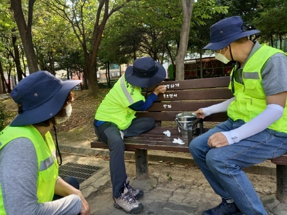 NSP통신-23일 궐동행복마을관리소 관계자들이 공원벤치에 힐링 문구를 그려 넣고 있는 모습. (오산시)