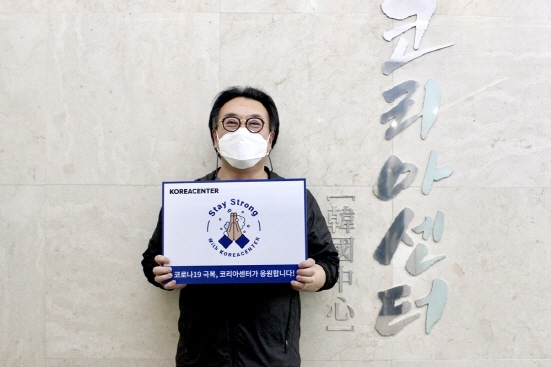 NSP통신-코로나19 극복 코리아센터가 응원한다는 문구가 적힌 손 팻말을 들고 있는 김기록 대표 (코리아센터 제공)