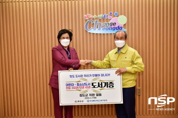 -이승율 청도군수(오른쪽)이 지난 9월 신축한 청도도서관에 군 전체 직원이 참여해 마련한 도서를 김금주 교육장(왼쪽)에게 전달하고 있다 (청도군)