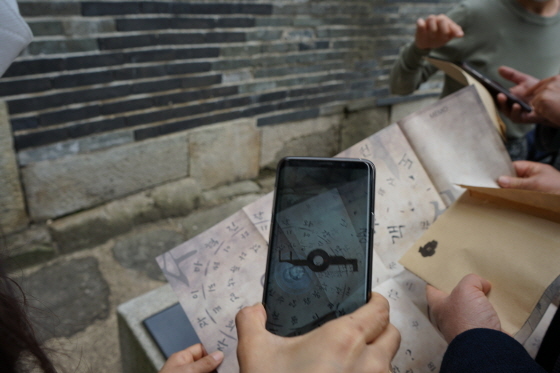 NSP통신-관람객들이 수원화성의 비밀을 풀기 위해 스마트폰 앱으로 콘텐츠를 확인하고 있다. (수원문화재단)