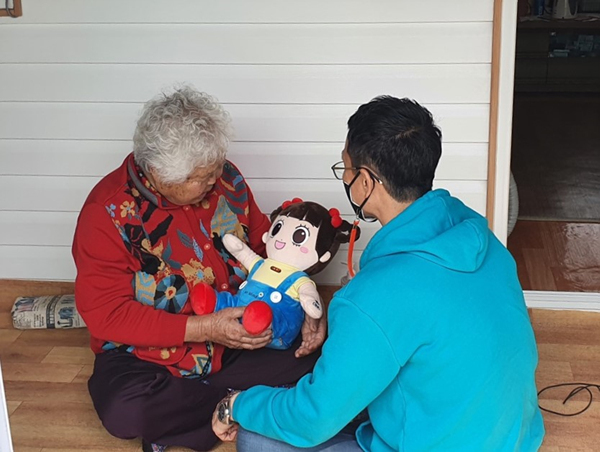 NSP통신-어르신 한분이 말동무 인형(AI 로봇)을 안고 사용법을 익히고 있다 (청도군)