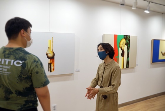 NSP통신-강윤정 작가(오른쪽)가 유디갤러리를 찾은 관람객에게 작품을 설명하는 모습 (유디치과)