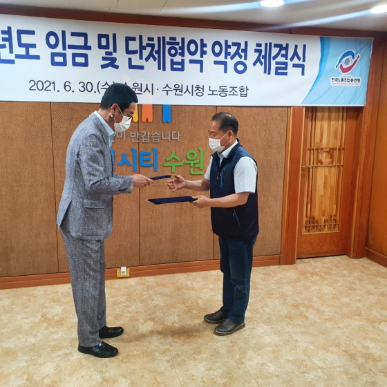 NSP통신-지난달 30일 김기배 환경국장(왼쪽)이 김성복 노동조합위원장과 협약서를 교환하는 모습. (수원시)