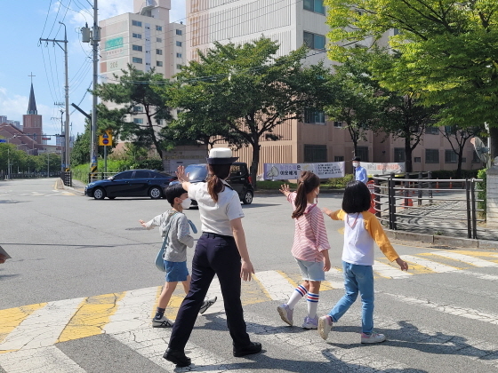 NSP통신-경찰관과 학생들이 아이언맨처럼 손을 뻗으며 횡단보도를 건너고 있다. (한국교통안전공단 경기남부본부)