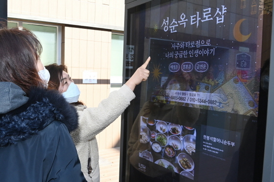 NSP통신-시민들이 수원시 팔달구 남문로데오거리에 설치된 디지털 옥외광고물에 송출되는 지역 업체 광고를 살펴보고 있다. (수원시)