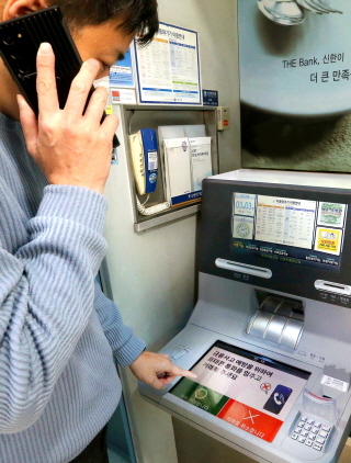 NSP통신-핸드폰 통화하며 신한은행 AI 이상행동탐지 ATM을 이용하고 있는 도중 ATM 화면에 금융사고 예방 주의 문구가 나온다. (신한은행)