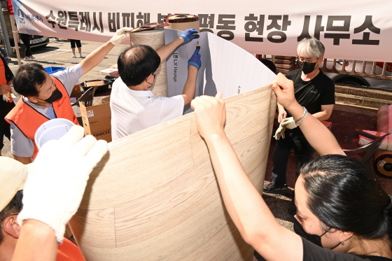 NSP통신-봉사자들이 침수 가구에 시공할 장판을 자르고 있다. (수원시)