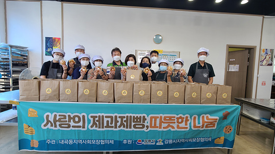 NSP통신-강릉시 내곡동지역사회보장협의체 위원들이 관내 어르신, 한부모, 다문화 가정 등에 전달할 빵꾸러미를 만든 가운데 전달에 앞서 기념촬영을 하고 있다. (강릉시)