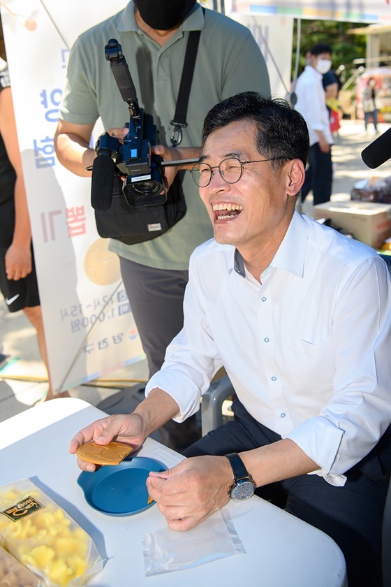 NSP통신-추석 직거래 장터에 마련된 달고나 체험 코너에 참여한 이기재 양천구청장이 해맑게 웃고 있다. (양천구)