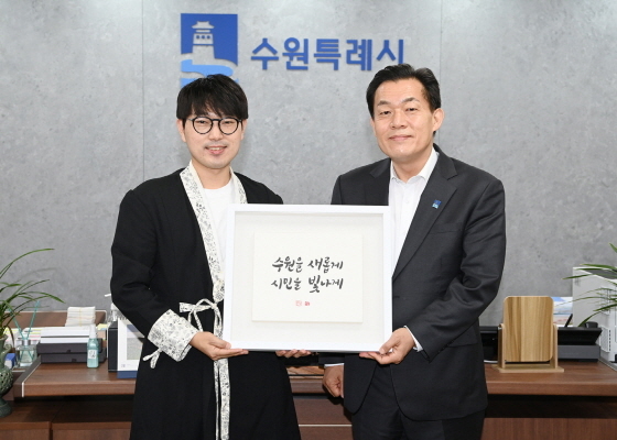 NSP통신-2일 이재준 수원시장(오른쪽)과 김상훈 작가가 수원을 새롭게 시민을 빛나게 VI 켈리그래피를 들고 기념촬영을 하는 모습. (수원시)