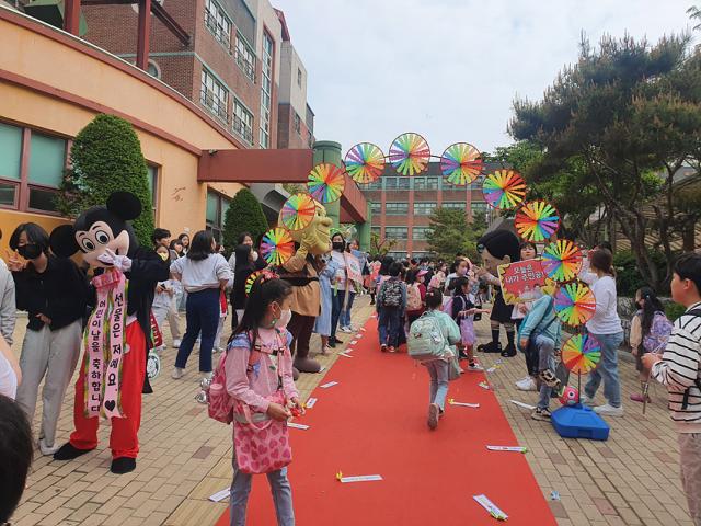 NSP통신-김포 유현초에서 제101주년 어린이날을 맞아 레드 카펫을 깔고 교장선생님이 직접 애니메이션 캐릭터로 분장해 학생들을, 학부모회에서는 학생들을 응원하는 문구가 적힌 피켓을 들고 학생들을 맞이하는 등굣길 이벤트를 하고 있다. (사진 = 김포교육지원청)