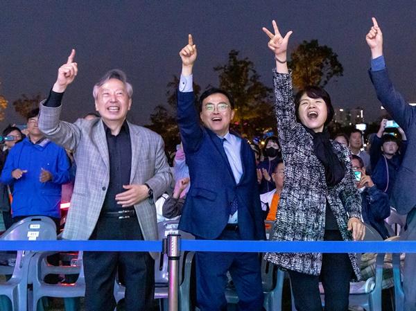 NSP통신-진교훈 서울 강서구청장(가운데)이 서울식물원 일대에서 열린 제21회 허준축제에서 지역 주민들과 함께 자리에서 일어나 공연을 즐기고 있다. (사진 = 강서구)