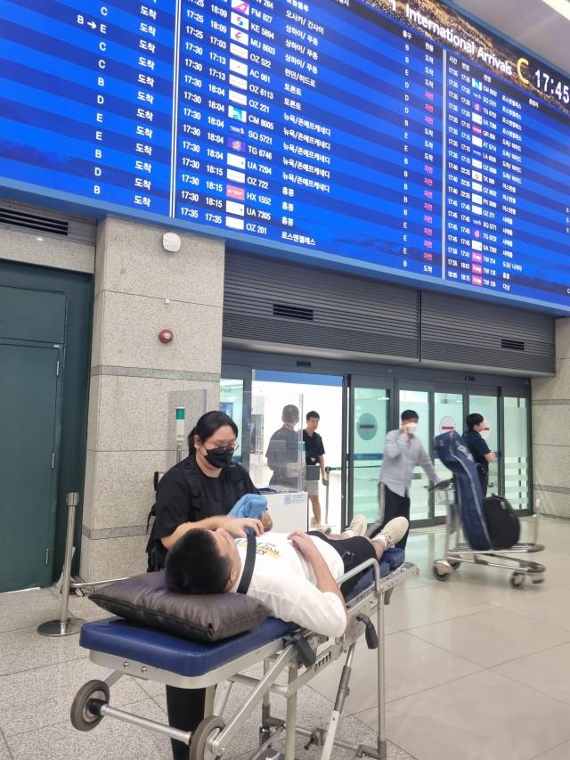 NSP통신-25일 환자이송침대에 실려 인천국제공항 입국장에 들어서는 백씨 모습. (사진 = 성남시)