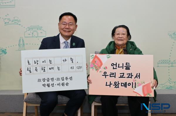 NSP통신-김재욱 칠곡군수와 천재교과서에 자신의 시가 실린 이원순 할머니가 교과서 수록을 기념하는 푯말을 들고 있다. (사진 = 칠곡군)