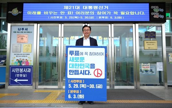 NSP통신-윤병태 나주시장이 제21대 대통령선거 사전투표 및 본 투표일을 안내하는 피켓을 들고 시민들의 투표를 독려하고 있다. (사진 = 나주시)