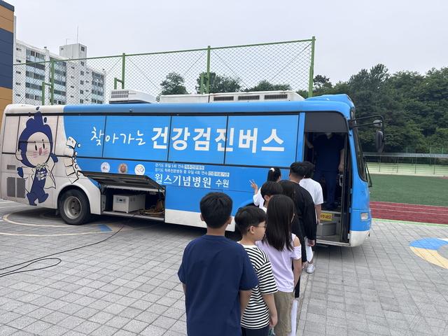 NSP통신-윌스기념병원 찾아가는 건강검진버스에서 학생들이 검진을 받기 위해 줄을 서 있다. (사진 = 수원시)