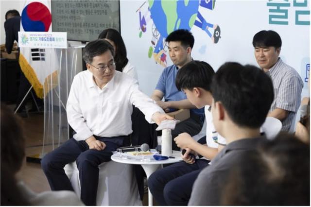 NSP통신-김동연 도지사가 지난달 30일 시흥에코센터에서 진행된 경기도 기후도민총회 출범식에서 땀 흘리는 학생 참가자에게 손수건을 건네고 있다. (사진 = 경기도)